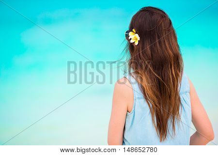 Young beautiful woman during tropical beach vacation. Enjoy suumer vacation alone on the beach at Africa with frangipani flowers in her hair