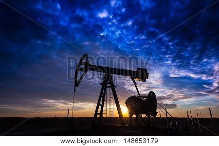 Oil and gas pump jack in Eastern European oil field, profiled on beautiful sunset colors