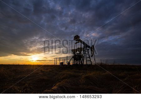 Oil derricks on a background of beautiful sunset with storm clouds