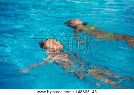 Happy Kids Playing In Blue Water Of Swimming Pool.