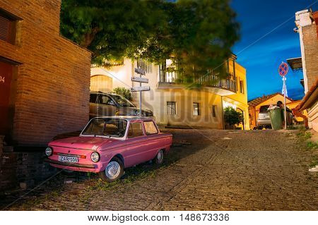 Tbilisi, Georgia - May 19, 2016: The Parked Rarity Tuning Pink Minicar ZAZ-968M Zaporozhets On The Street Paved By The Cobblestone In Old District Of The City In Summer Evening.