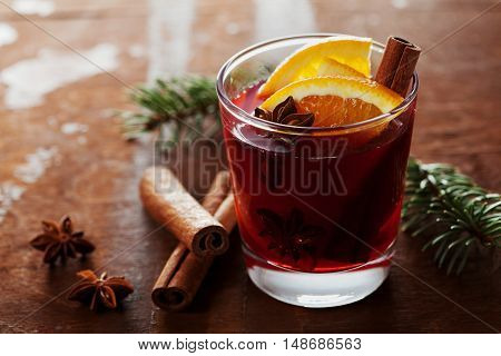 Christmas mulled wine or gluhwein with spices and orange slices on rustic table, traditional drink on winter holiday, magic light, selective focus.