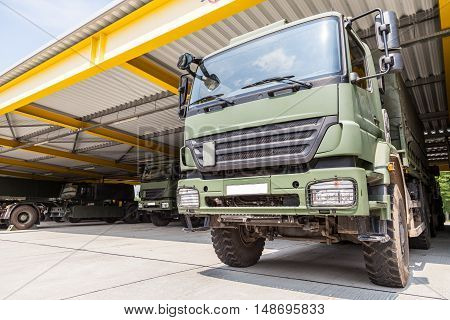 a military truck stands under military roof