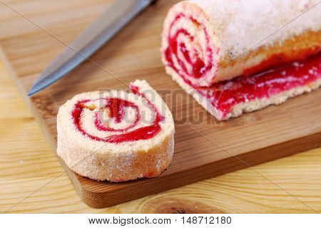Sweet Roll With Jam And A Knife On A Cutting Board.