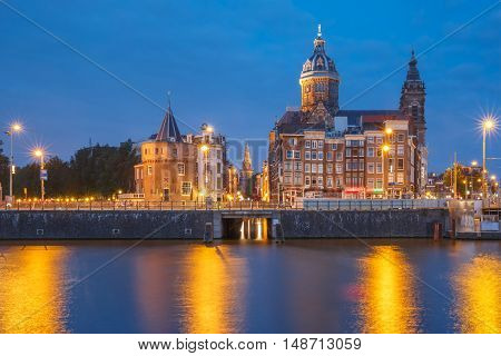 Night panoramic city view of Amsterdam canal, bridge and Basilica of Saint Nicholas, Holland, Netherlands. Long exposure.