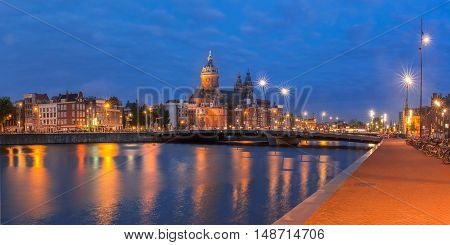 Night panoramic city view of Amsterdam canal, bridge and Basilica of Saint Nicholas, Holland, Netherlands. Long exposure.