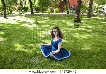 Girl meditating in a park sitting in the lotus position