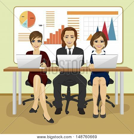 Happy business people sitting with their laptops in the office in front of graphs and charts