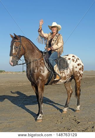 cowgirl on appaloosa horse on the beach