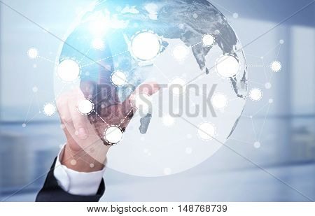 Man's hand touching a screen with globe and startup icons. Concept of international trade.Toned image. Double exposure