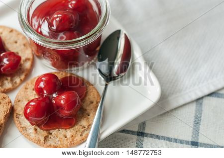 cherry topping dessert on cracker bread white plate
