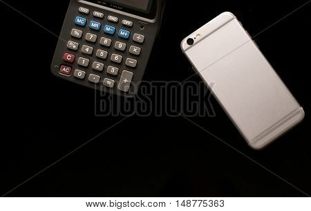 Smartphone and calculator use in business office black background