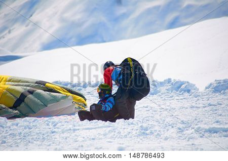 Paragliders tandem after landing in winter snow mountains. Extreme sport health weekend or holiday