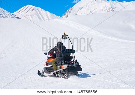 man drive snowmobile in mountains. ski resort staff. extreme driving with perfect winter landscape. Snow riding to the peak.