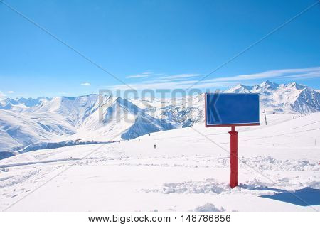 Bird view on the ski village in valley. Background of snowboard resort from the high peak. Winter season for advertising or billboard. Copy space on the sign.