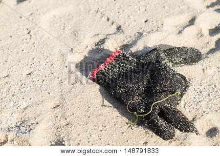 Used cotton glove on the beach garbage selective focus .