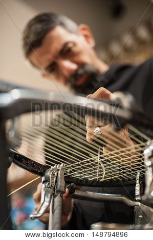 Tennis Stringer Holding Awl And Doing Racket Stringing