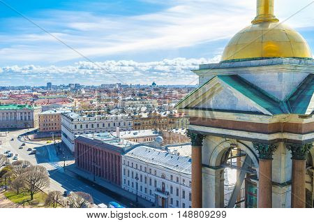 The view on the luxury mansions of St Isaac's Square and old roofs of St Petersburg from the rooftop of St Isaac's Cathedral with its golden domed bell tower on the foreground Russia.