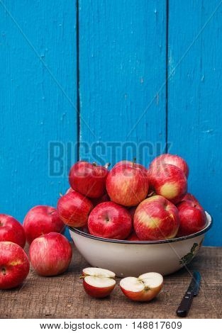 Juicy organic red ripe whole and sliced apples on a wooden table on a blue background. A rustic style. Selective focus