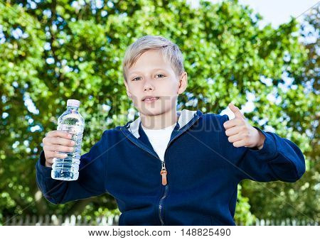 Young teenage boy with bottle of water in park sitting on the bench