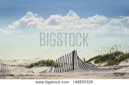 Good background shot of puffy clouds and blue sky with sand fence in the dunes on a sunny day at Florida Beach.