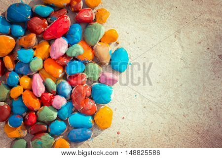 Colored stones colored paints in different colors lie on a flat surface. Second half empty. Close-up
