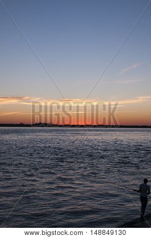 Silhouette of a fisherman on a sunset background