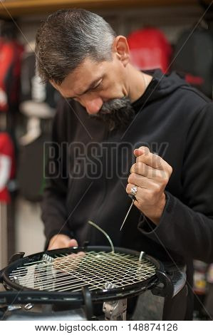 Tennis Stringer Holding Awl And Doing Racket Stringing