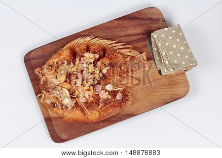 Deep fried fish ,Nile tiapia, with crispy garlic on butcher served.