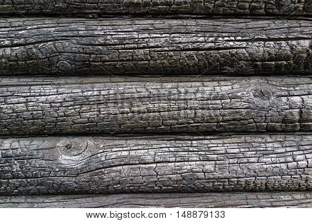 Charred wall of the house of pine trees logs. Burnt wall of the house. Conceptual background charred walls of the timber. Burnt pattern. Burnt wooden house wall. Black burned wooden house texture.