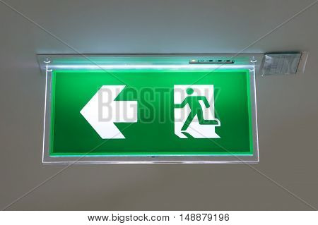green emergency exit sign showing the way to escape