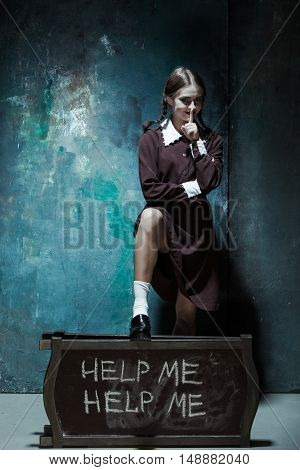 Halloween theme: Portrait of a young smiling girl in school uniform as killer woman against school board . The image in the style of Halloween and Addams family