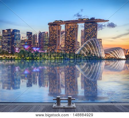 Singapore, Republic of Singapore - May 4, 2016: Supertree grove, Cloud garden greenhouse and Marina Bay Sands hotel reflecting in water at dusk with glowing lights