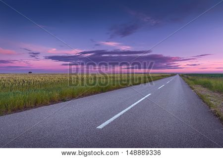 Driving on an empty asphalt road through the agricultural fields at idyllic sunset. Titel hill Serbia.