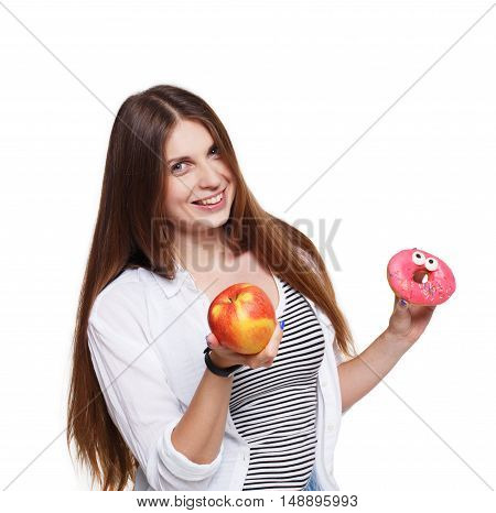 Choose healthy food, diet concept. Beautiful long-haired young woman with big ripe red apple in one hand and a donut in another. Female portrait isolated on white background.