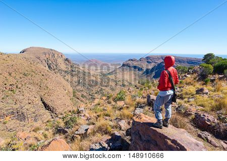 Tourist standing on rock and looking at the panoramic view in Marakele National Park one of the travel destination in South Africa. Concept of adventure and traveling people.