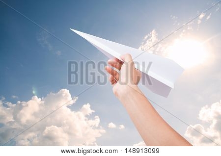 Hand holding paper plane toward cloudy blue sky concept new innovation and new creativity.