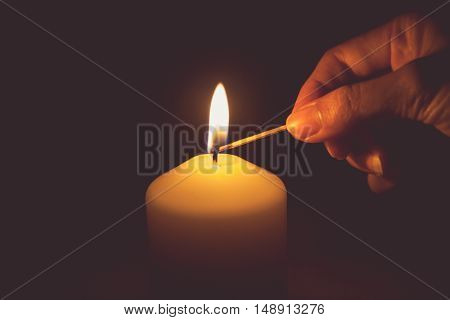 Vintage tone of hand with matchstick lighting a candle