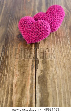 Two chrocheted hearts on a wooden bacground. Soft focus on a nearest heart.