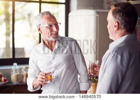 Joyful celebration. Neatly dressed grey man in glasses looking at his colleague