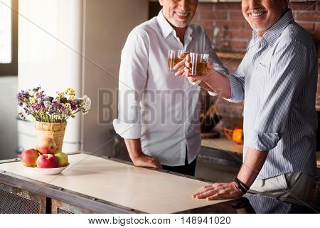 Glad and happy. Middle-aged males smiling at the camera while having their whiskey