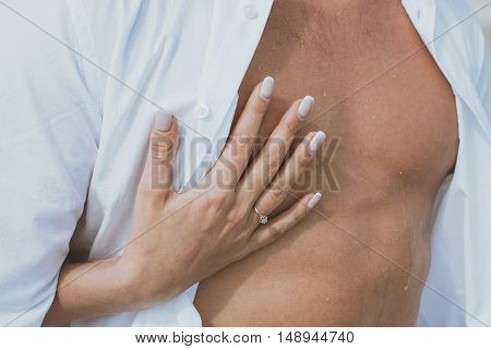 Sexy muscular naked man and female hands unbuckle his jeans.