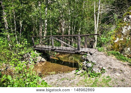 Small bridge lets hikers cross a  stream in a wooded area of Uvac . Serbia.