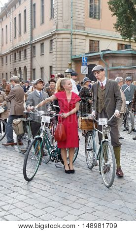 STOCKHOLM - SEPT 24 2016: Smiling woman dressed in a red dress leading bicycles in the Bike in Tweed event September 24 2016 in Stockholm Sweden