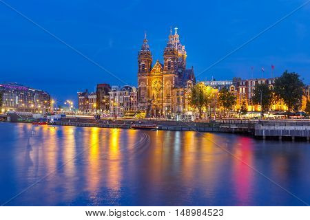 Night panoramic city view of Amsterdam canal, bridge and Basilica of Saint Nicholas, Holland, Netherlands. Long exposure.