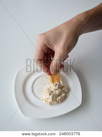 Closed Up Hand Dipping Tuna Spread In White Plate With Mini Cracker. Quick Healthy Snack.