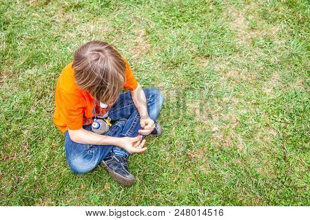 Single Bored Teen Boy Sitting On Green Lawn
