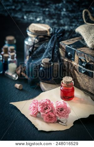 Love Potion. Magic Concept Wit Red Liquid In Small Bottle, Wooden Box, Old Paper And Flowers