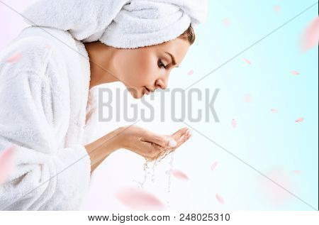 Young Woman Washing Face With Clean Water In White Bathrobe And Towel.