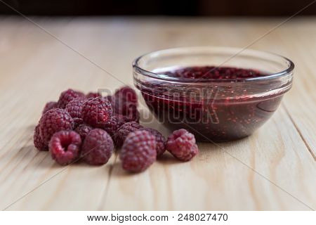Homemade Raspberry Jam In A Glass Bowl With Fresh Ripe Organic Raspberries On A Wooden Table